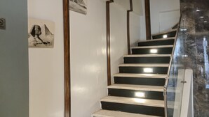 Una escalera con peldaños blanco y negro, barandillas de madera e iluminación empotrada en la pared.