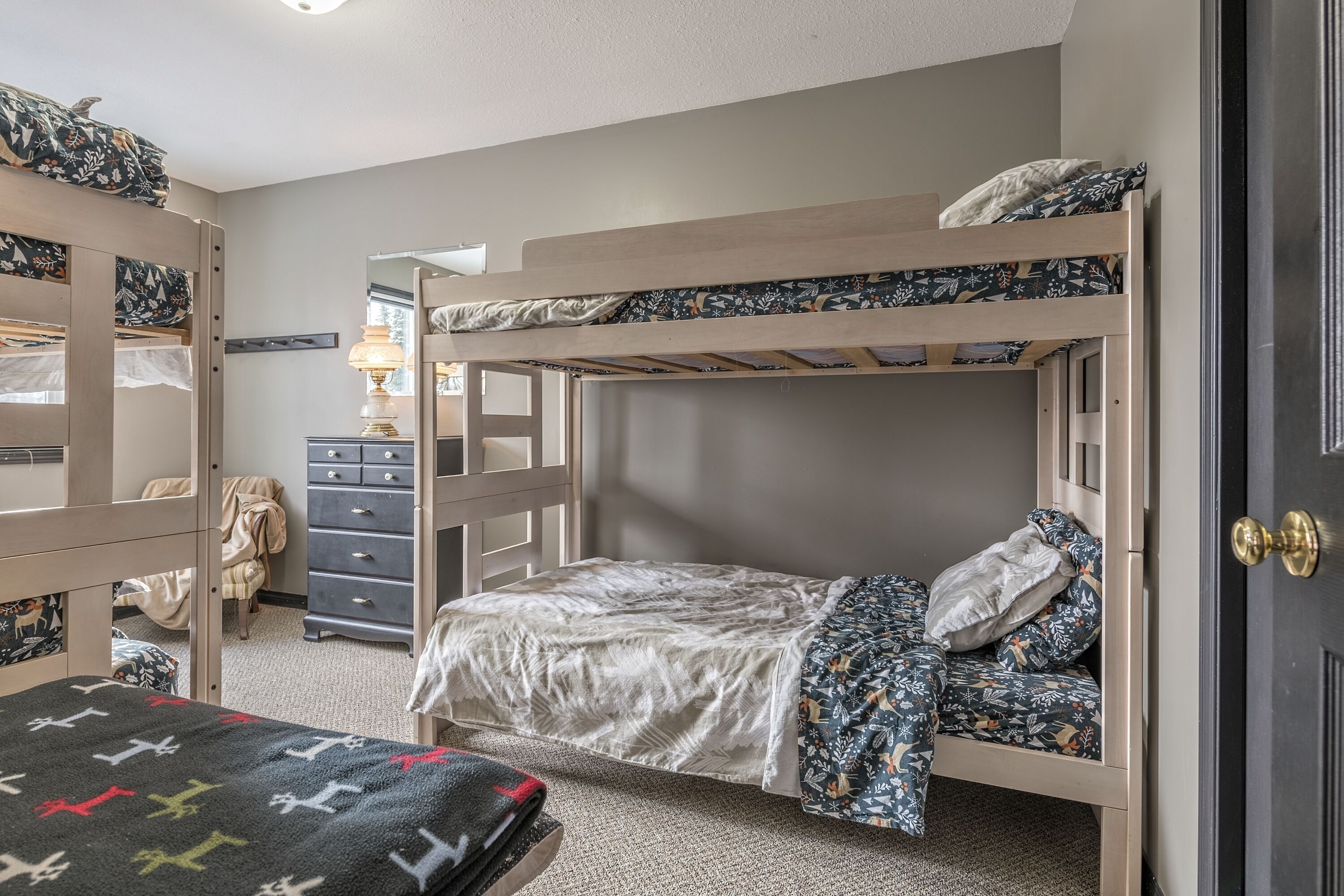 A bunk bed room with a dresser and a lamp.