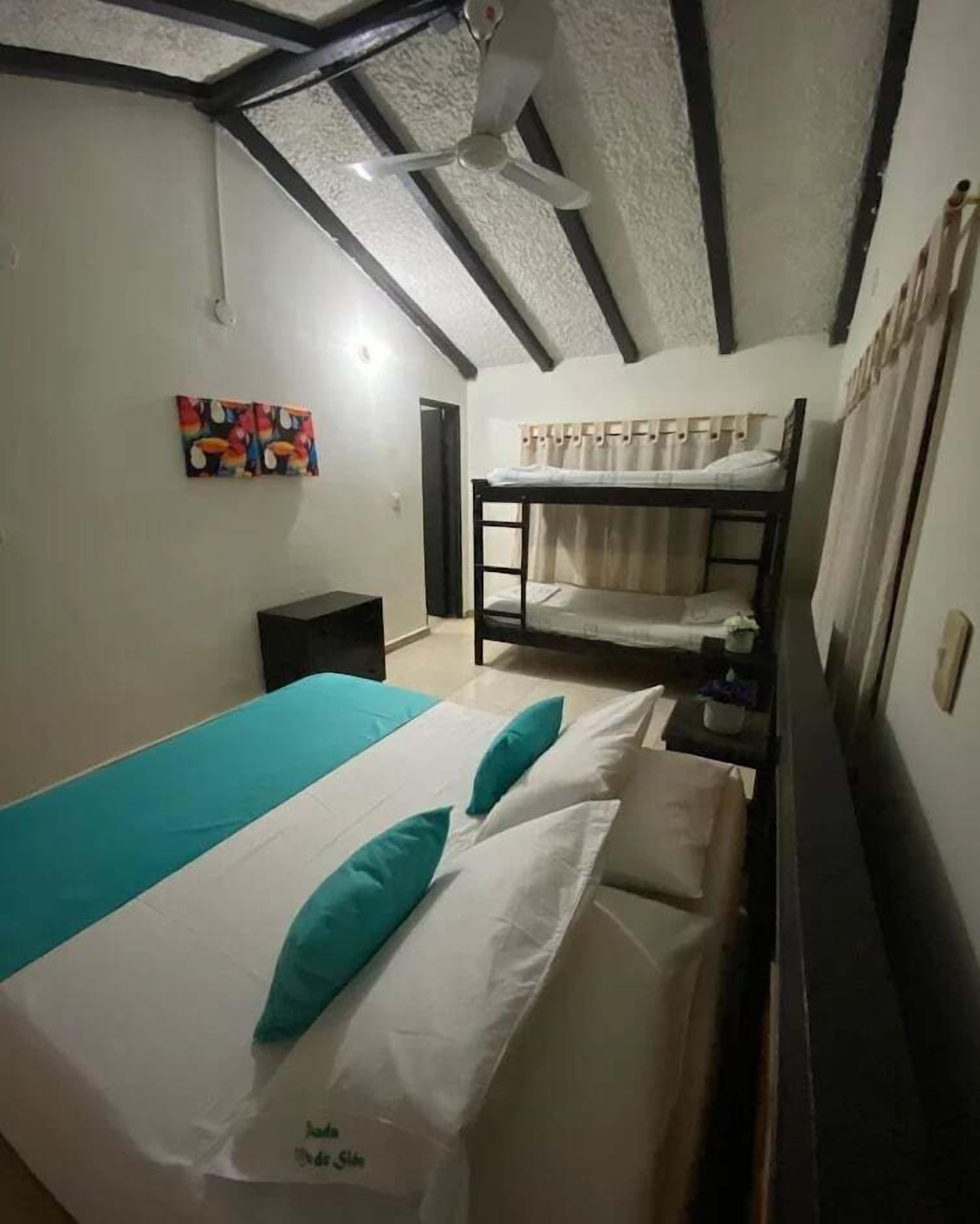 Una habitación con literas, ventilador de techo y un cuadro en la pared.