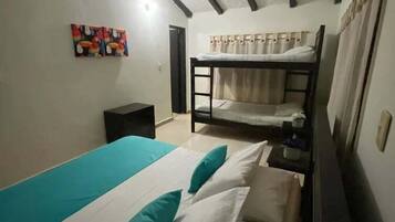 Una habitación con literas, ventilador de techo y un cuadro en la pared.