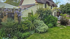 A house with a thatched roof, surrounded by a well-maintained garden with various plants and shrubs. - 4 bedroom accommodation in Lymington (Lymington)