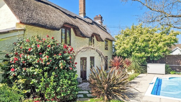 A house with a thatched roof, a swimming pool, and a garden with various plants and flowers. - 4 bedroom accommodation in Lymington (Lymington)