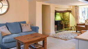 A cozy living room with a blue sofa, a wooden coffee table, and a fireplace. - 4 bedroom accommodation in Lymington (Lymington)