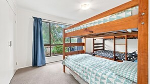 A bunk bed room with a window, curtains, and a carpeted floor.