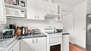 Una cucina moderna con mobili bianchi, forno integrato e microonde.
