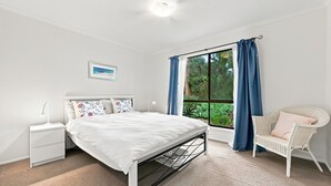 A bedroom with a bed, a nightstand, a chair, a window with curtains, and a picture on the wall. - Kyeema Inverloch, Wifi and Pet friendly outside only (Inverloch)
