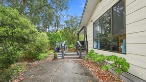 A house with a covered outdoor area, a staircase leading to a deck, and a garden with various plants. - Kyeema Inverloch, Wifi and Pet friendly outside only (Inverloch)