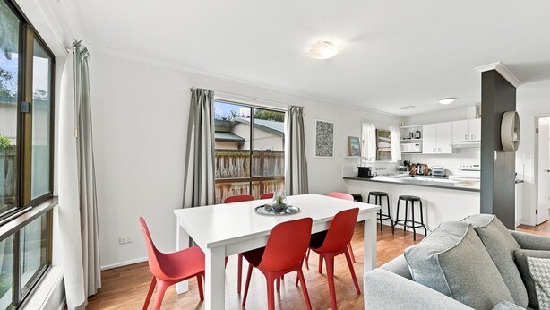 A modern kitchen with white cabinets, a dining area with a white table and red chairs, and a grey sofa. - Kyeema Inverloch, Wifi and Pet friendly outside only (Inverloch)