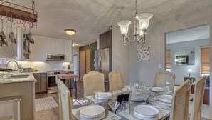Une salle à manger moderne avec une table en verre, dressée pour six personnes, entourée de chaises en osier.