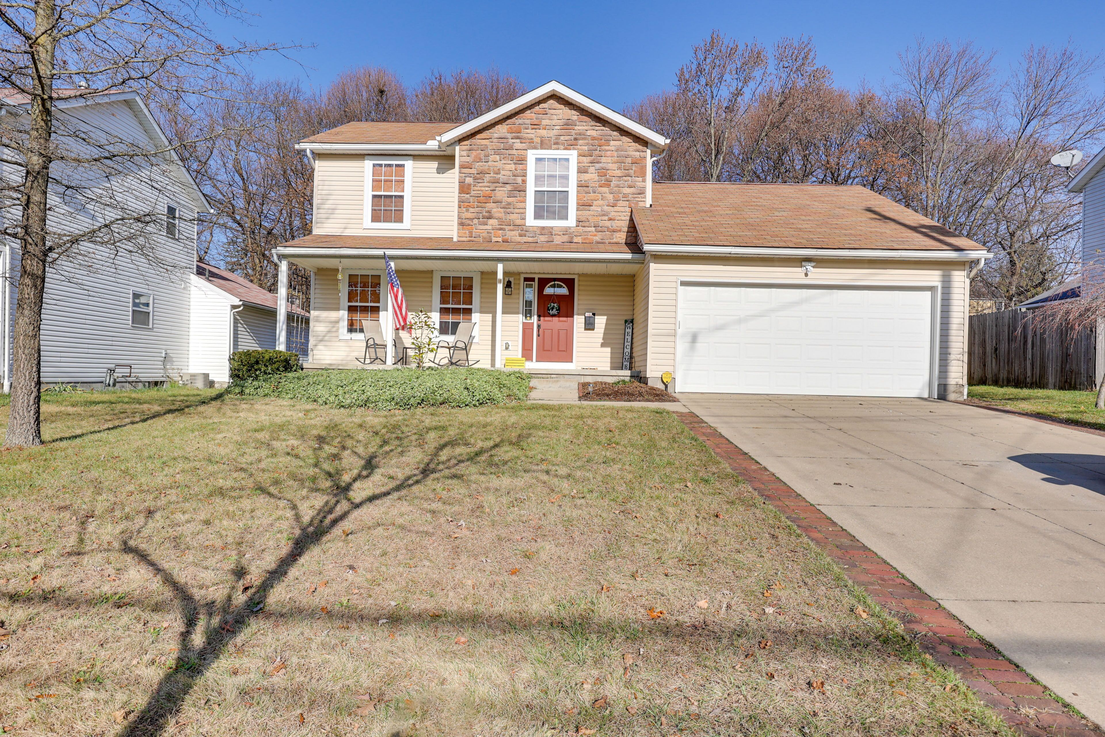 A two-story house with a front porch, a garage, and a well-maintained lawn.