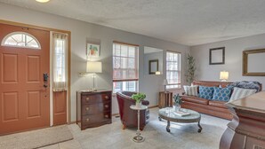 Un salon avec un canapé en cuir marron, une table basse, une cheminée et une porte avec une fenêtre.