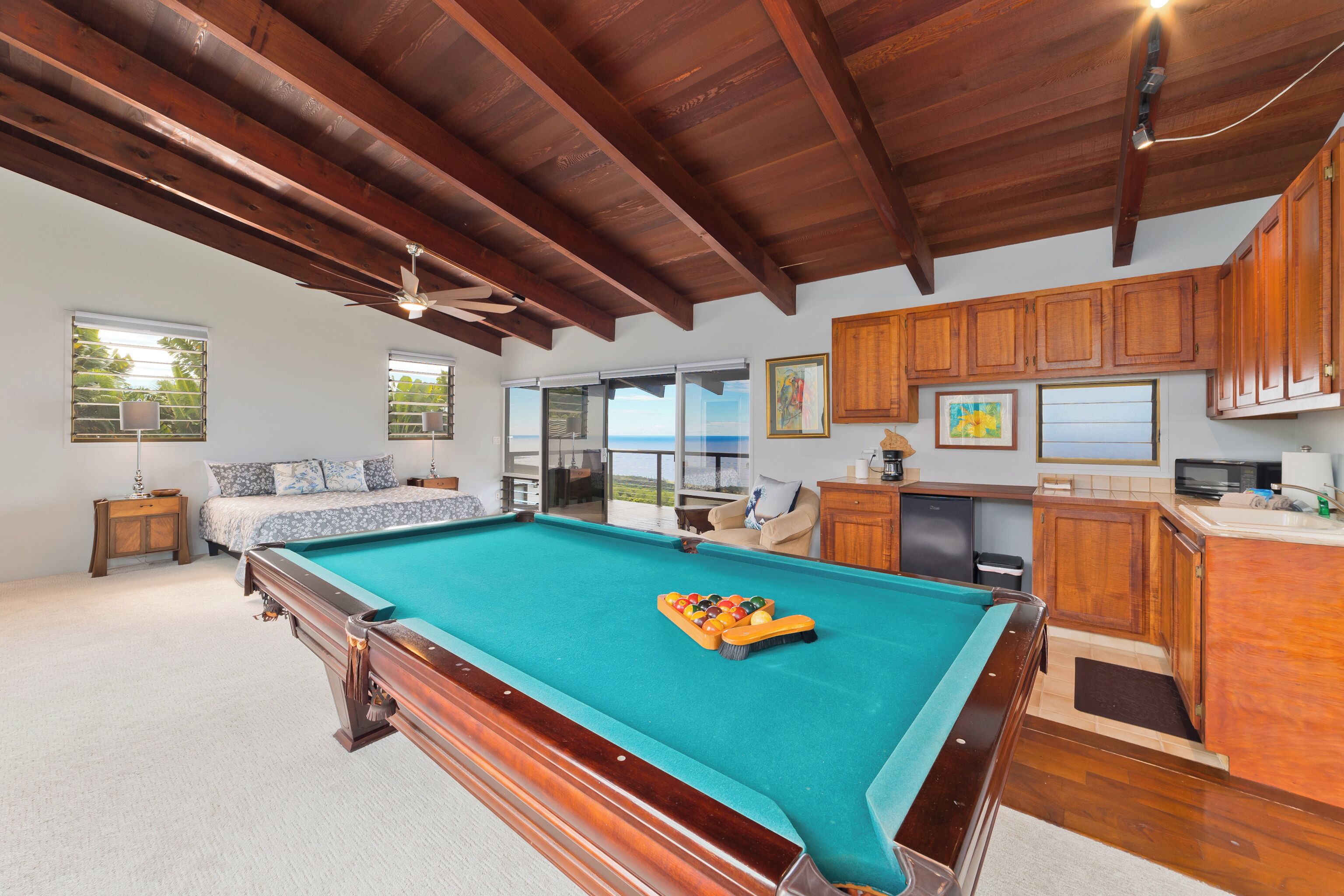 Un vaste espace de vie comprenant une table de billard, des meubles en bois et une vue sur l’extérieur.