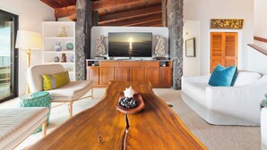 Een moderne woonkamer met een houten salontafel, witte banken, een televisie en een stenen open haard.