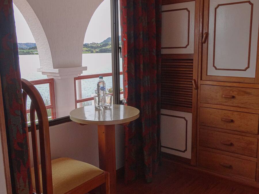 A room with a wooden chair, a small round table, and a cabinet with drawers.