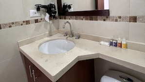 A bathroom with a sink, mirror, and toiletries.