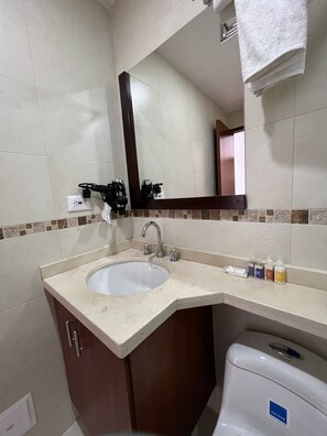 A bathroom with a sink, mirror, and toiletries.