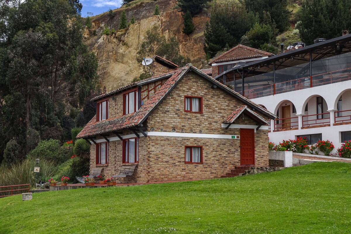 Una casa de piedra con puerta roja, un balcón y vistas a un paisaje montañoso.