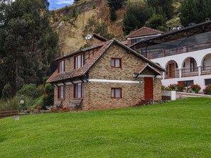A stone house with a red door, a balcony, and a view of a mountainous landscape.