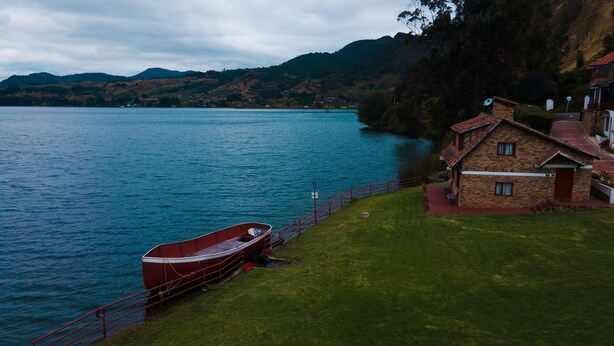 A lakeside house with a boat docked by the water.