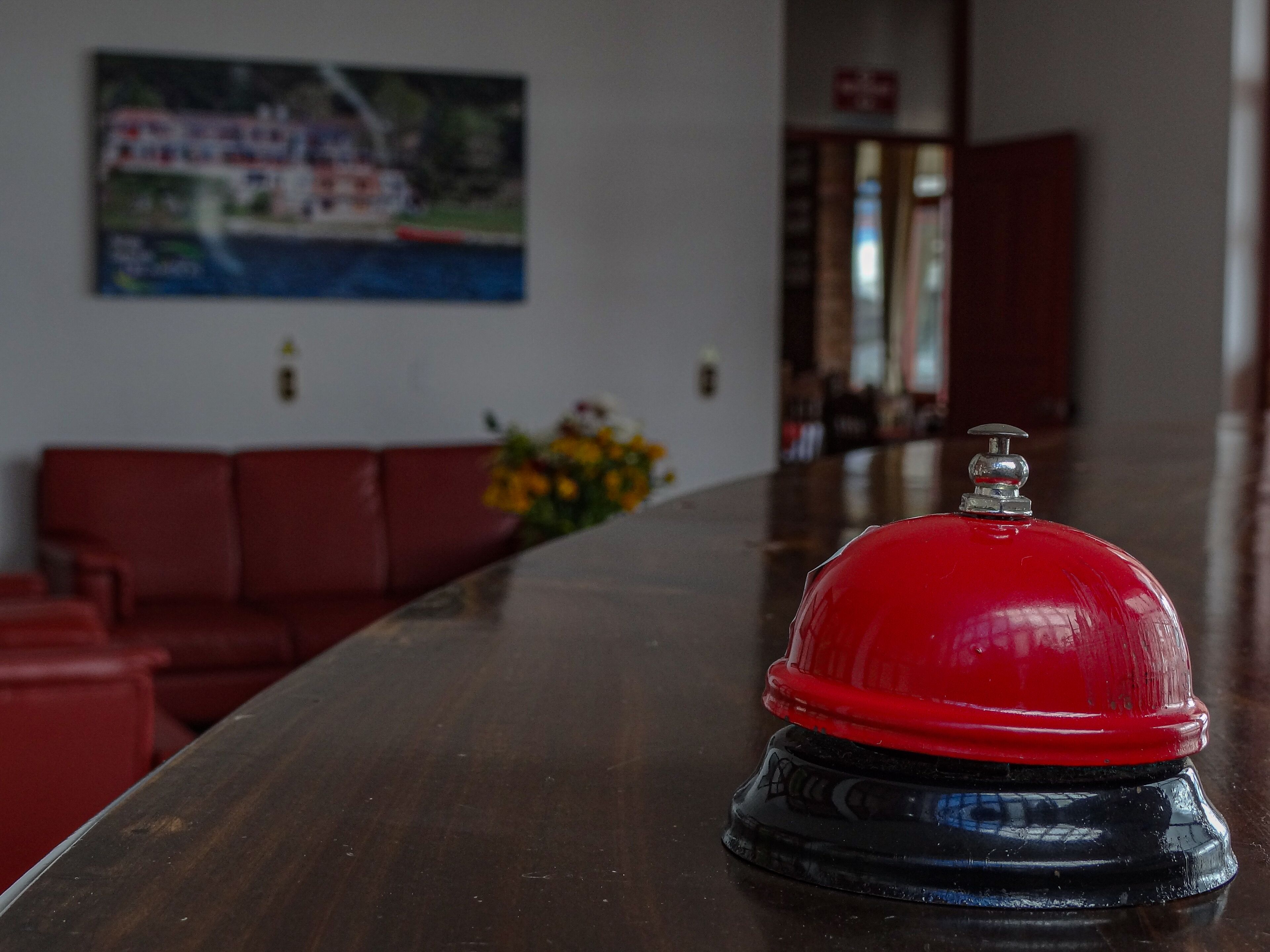 Un comptoir d’accueil d’hôtel rouge, avec une cloche et un vase à fleurs.