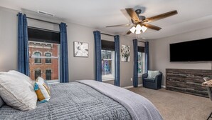 A bedroom with a large bed, a ceiling fan, a TV, and a dresser.