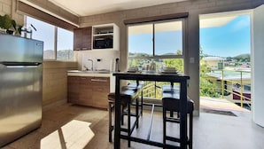 Una cocina moderna con un refrigerador de acero inoxidable, armarios de madera y un amplio ventanal con vista a la ciudad.