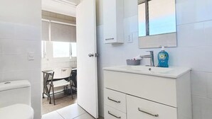 Un baño moderno con inodoro, lavabo con espejo y mueble.
