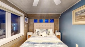 Une chambre avec un grand lit, une tête de lit en bois et une fenêtre donnant sur un beau paysage.