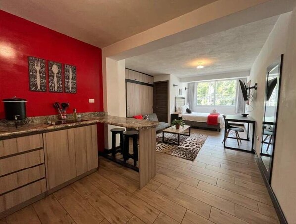 Cozy living space with a kitchen area, sofa, and large window offering a view of the outdoors.