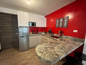 Modern kitchen with a stainless steel refrigerator, granite countertop, and wooden cabinet.