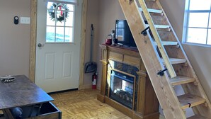 A room with a wooden staircase, a fireplace, and a door with a wreath.