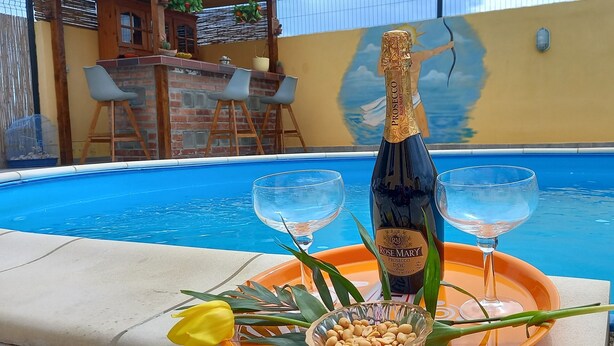 Et poolområde med en Prosecco DOCG, to glas, en bakke og et blomsterarrangement.