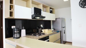 A compact kitchen with a stove, coffee maker, and a refrigerator.