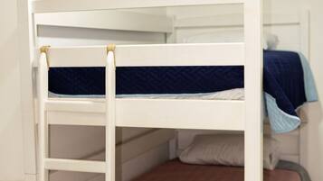 A bunk bed with a ladder, a single bed with a blue blanket, and a wall with three posters.