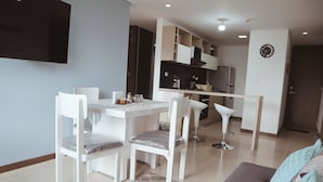 A modern living room with a dining area, a sofa, and a TV mounted on the wall.