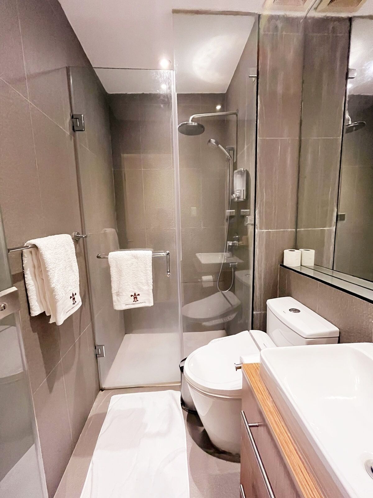 A modern bathroom with a glass-enclosed shower, a toilet, and a sink.