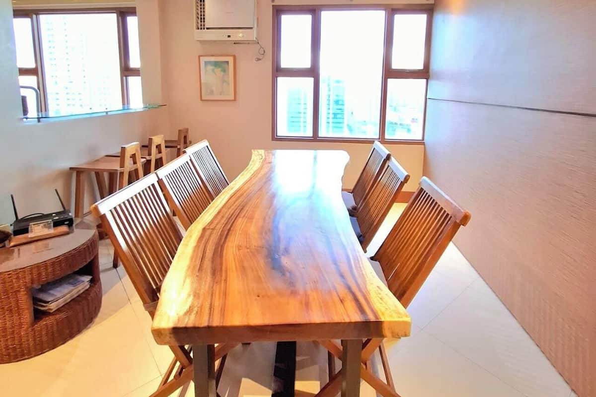A conference room with a long wooden table, chairs, and large windows.