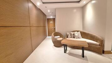 Un interior moderno con un panel de pared de madera, un sofá de mimbre con cojines estampados, una silla redonda de mimbre y una mesa de centro de madera.