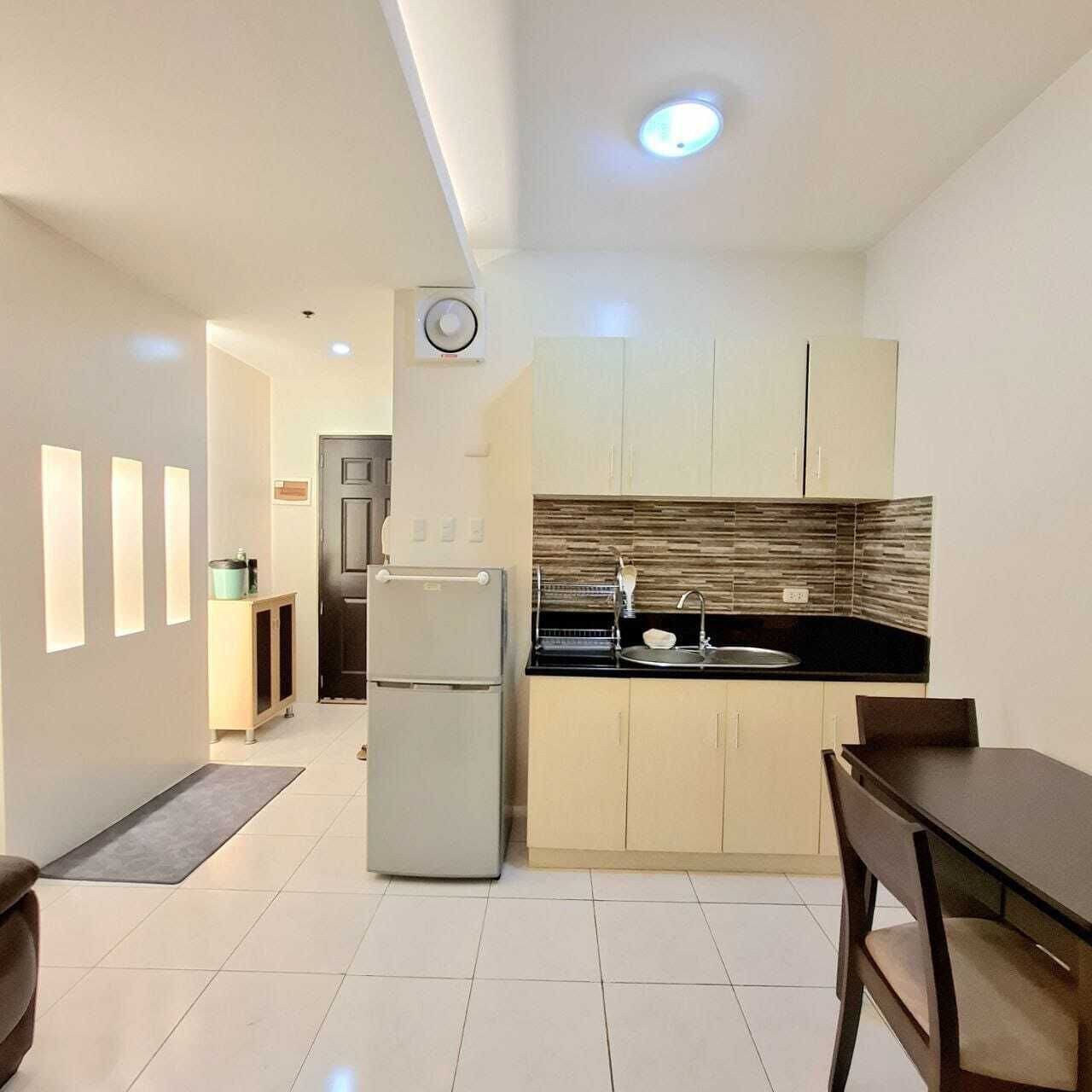 A compact kitchen with modern appliances, a dining area, and a visible door leading to another room.