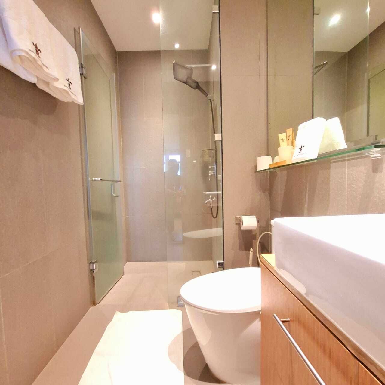 A modern bathroom with a glass-enclosed shower, a white toilet, and a vanity with a mirror and shelves.