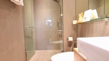 Ein modernes Badezimmer mit Duschkabine, einer weißen Toilette und einem Waschtisch mit Spiegel und Ablageflächen.