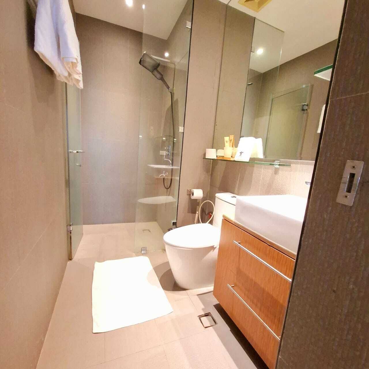 Un baño moderno con cabina de ducha de vidrio, inodoro blanco y tocador de madera con espejo.