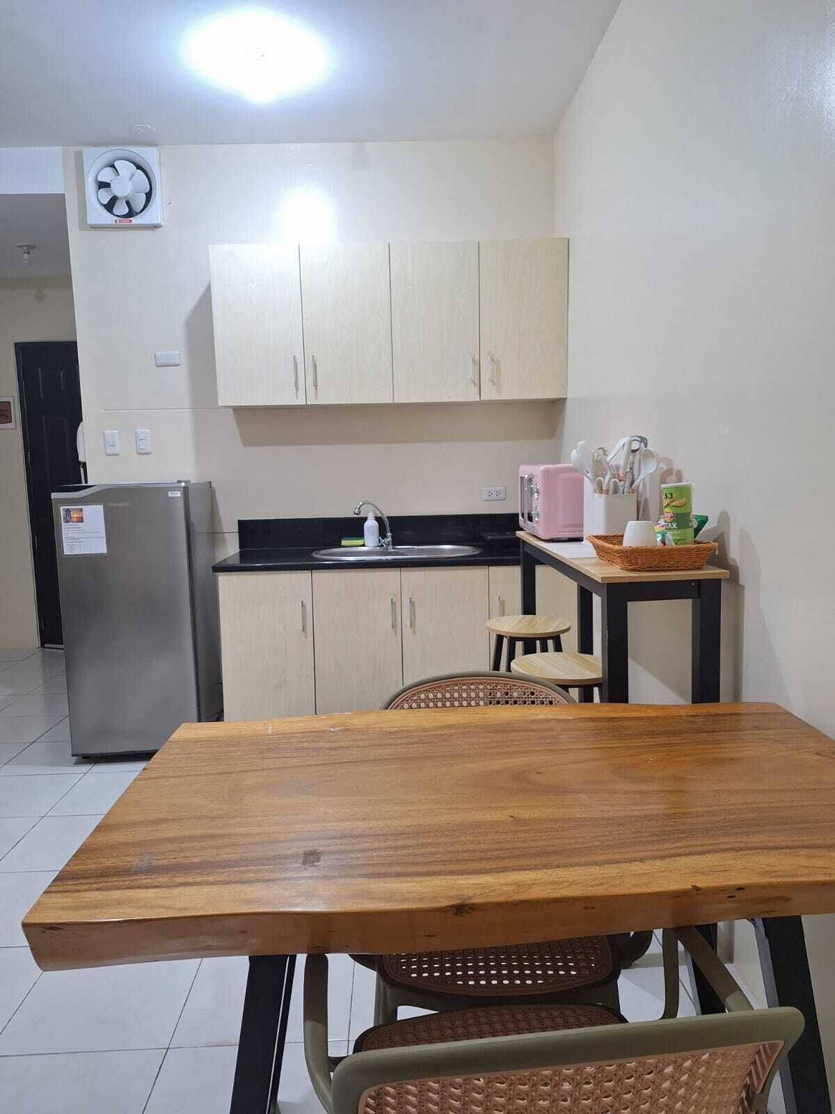 Une cuisine compacte comprenant une table à manger en bois, un réfrigérateur, un évier et un grille-pain.
