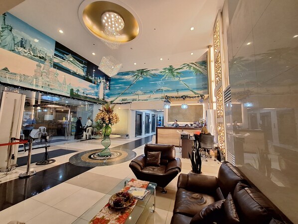 A lobby with a reception desk, seating area, and a mural of a cityscape. - StayLuxia Manilabayview (Manila)