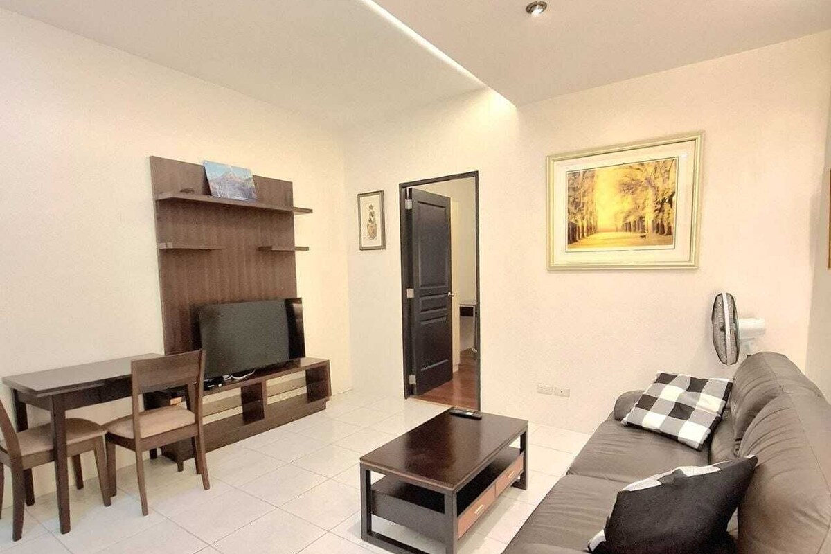 A living room with a sofa, a TV, a coffee table, and a dining area with chairs and a table.