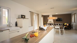 A modern kitchen with a wooden countertop, a built-in microwave, and a dining area with a table set for two. - Villa Pharia with Pool III (Stari Grad)