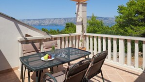 A balcony with a table and chairs, a potted plant, and a view of the sea and mountains. - Villa Pharia with Pool V (Stari Grad)