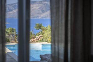 A view through a window of a swimming pool with a mountain backdrop. - Villa Pharia with Pool V (Stari Grad)