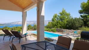 Un espace extérieur abrité comprenant une piscine, des chaises longues et une table.