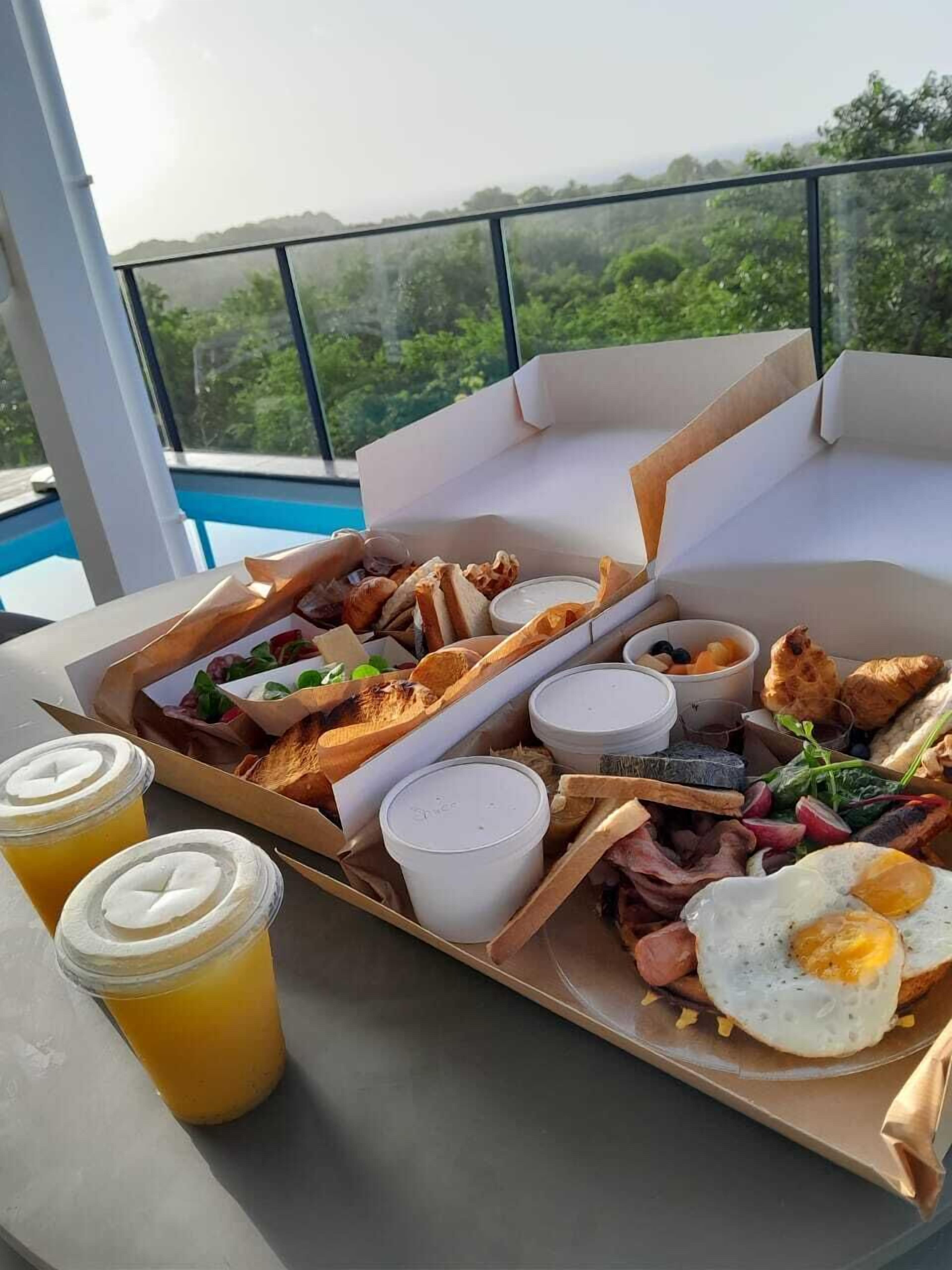 Ein Frühstücksbrett mit verschiedenen Speisen und Getränken auf einem Balkon mit Blick auf eine schöne Aussicht.